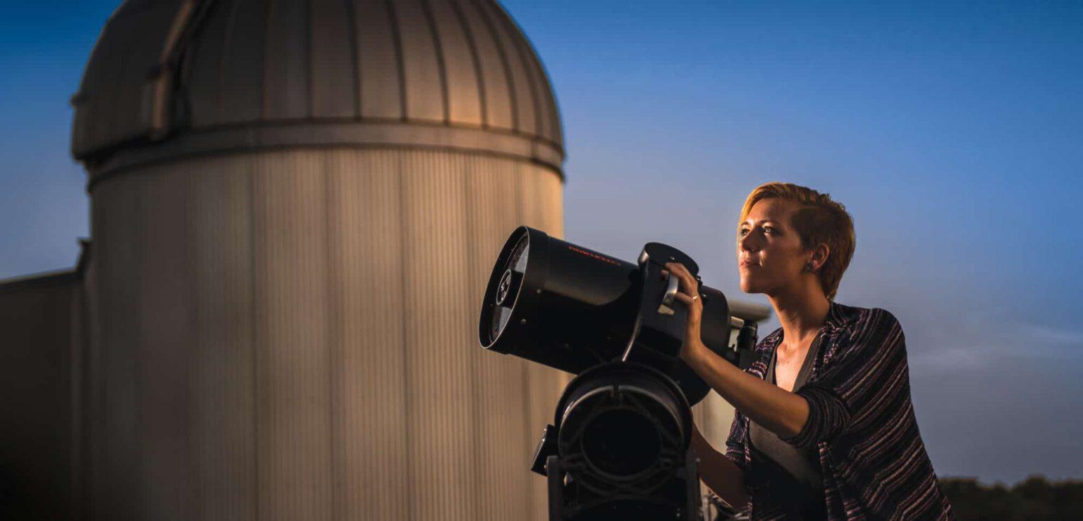 一个女学生用望远镜仰望天空.